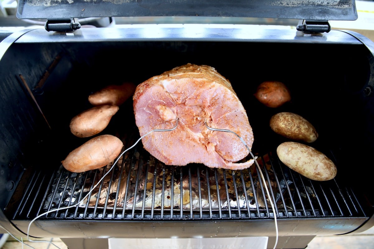 Spiral ham on a pellet grill with potatoes.