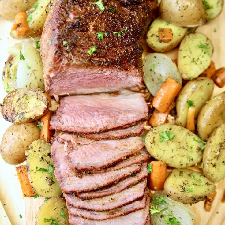 Overhead view of roast beef, sliced, potatoes, carrots, onions.
