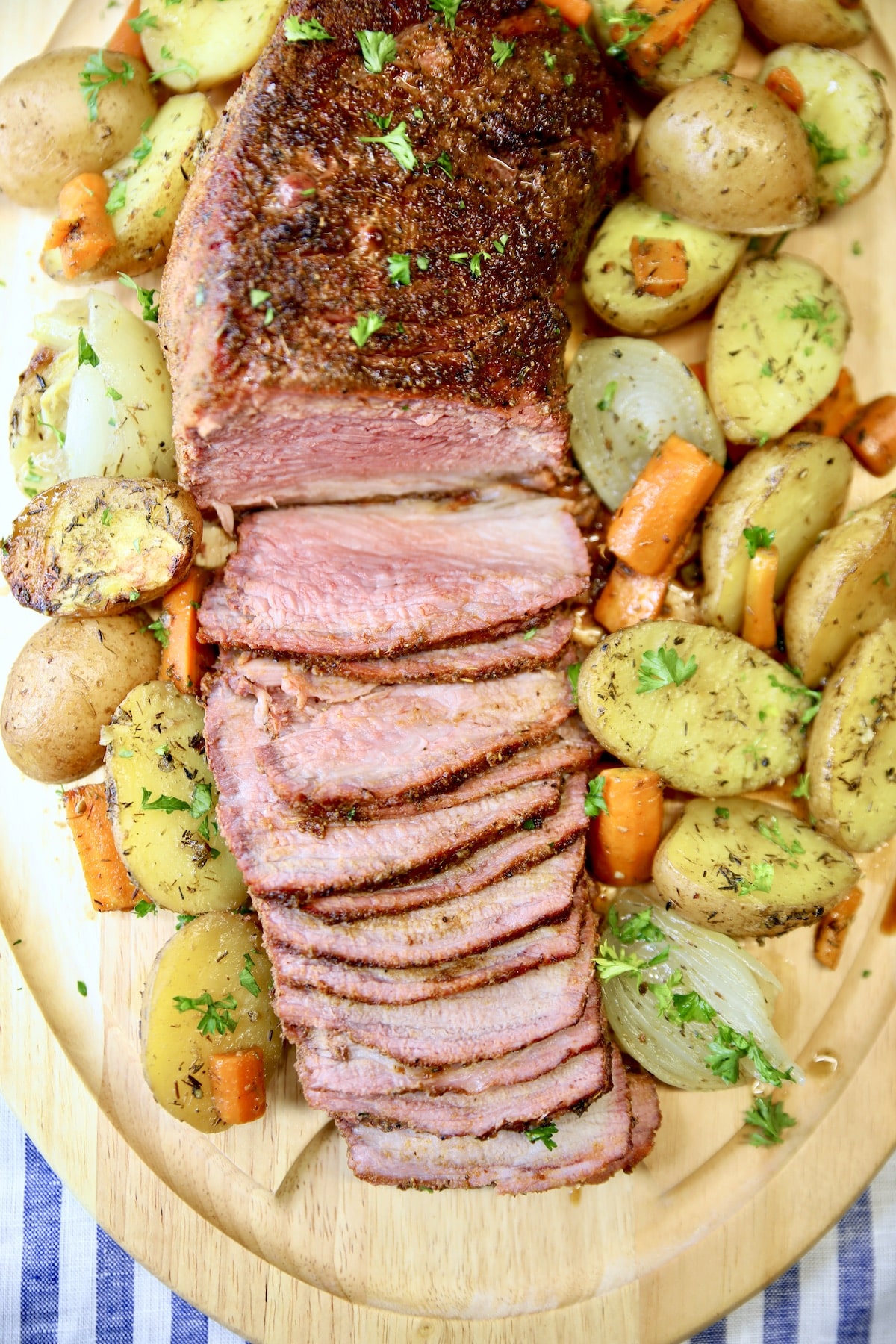 Cutting board with sliced roast beef and vegetables.