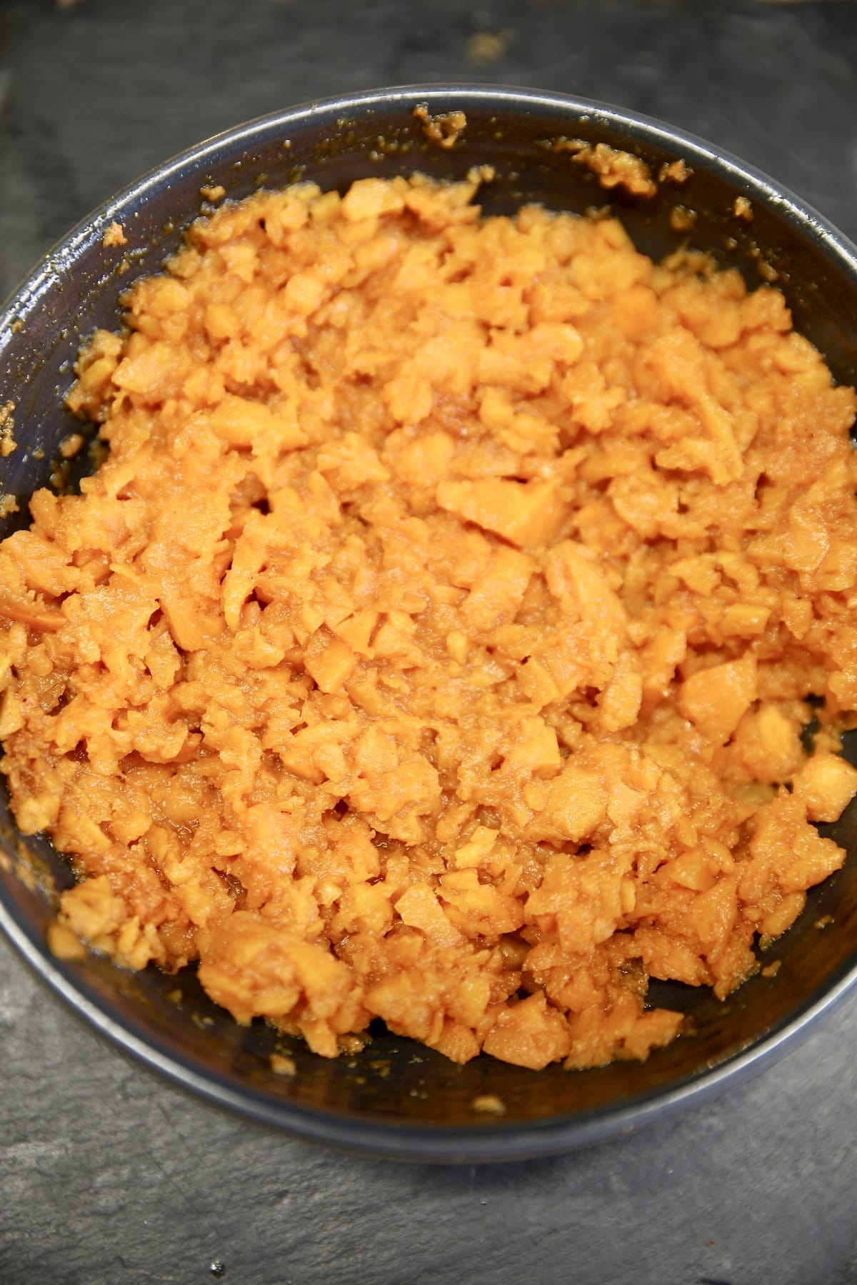 Bowl of coarsely mashed sweet potatoes.