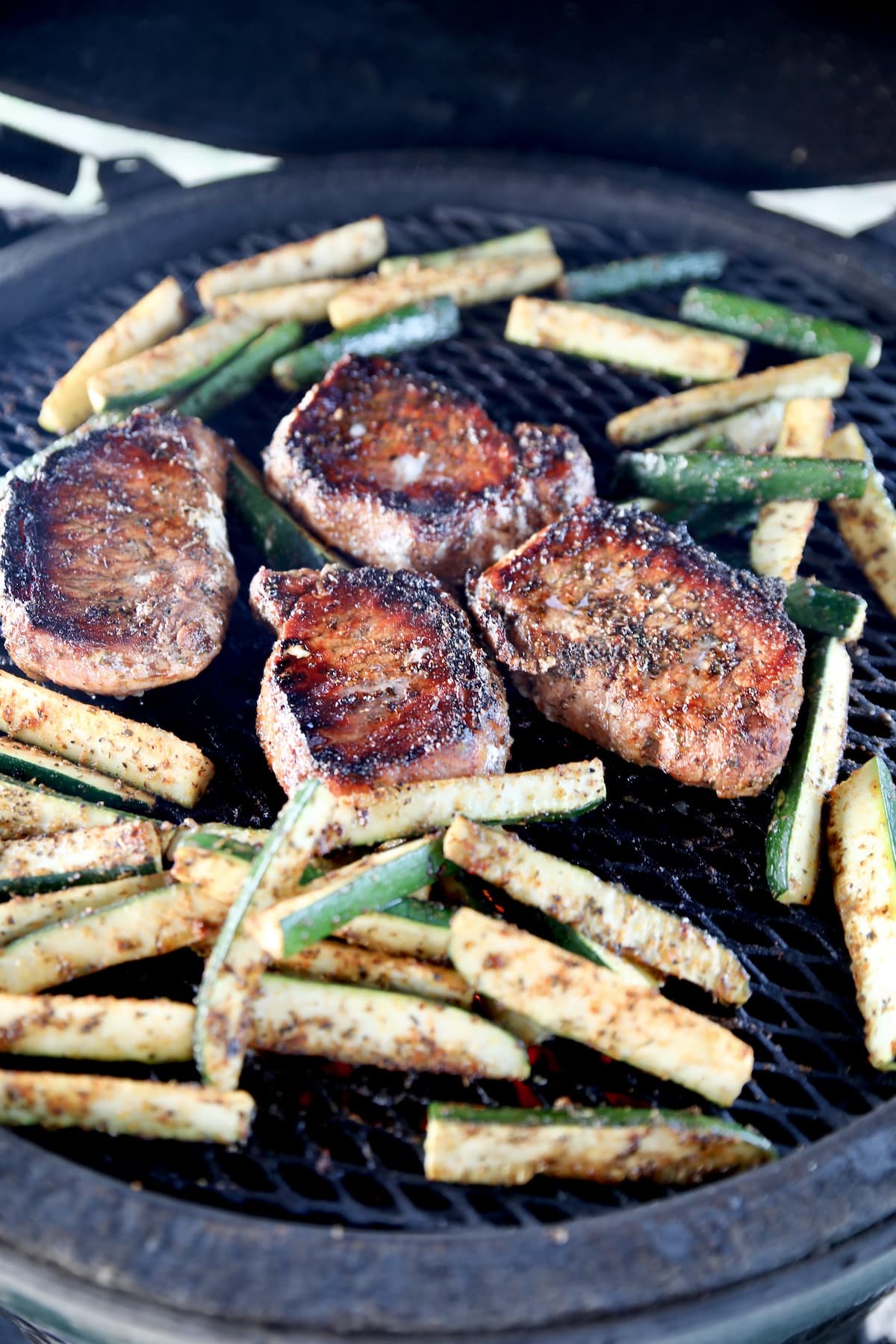 Grilled pork chops with zucchini on a grill.