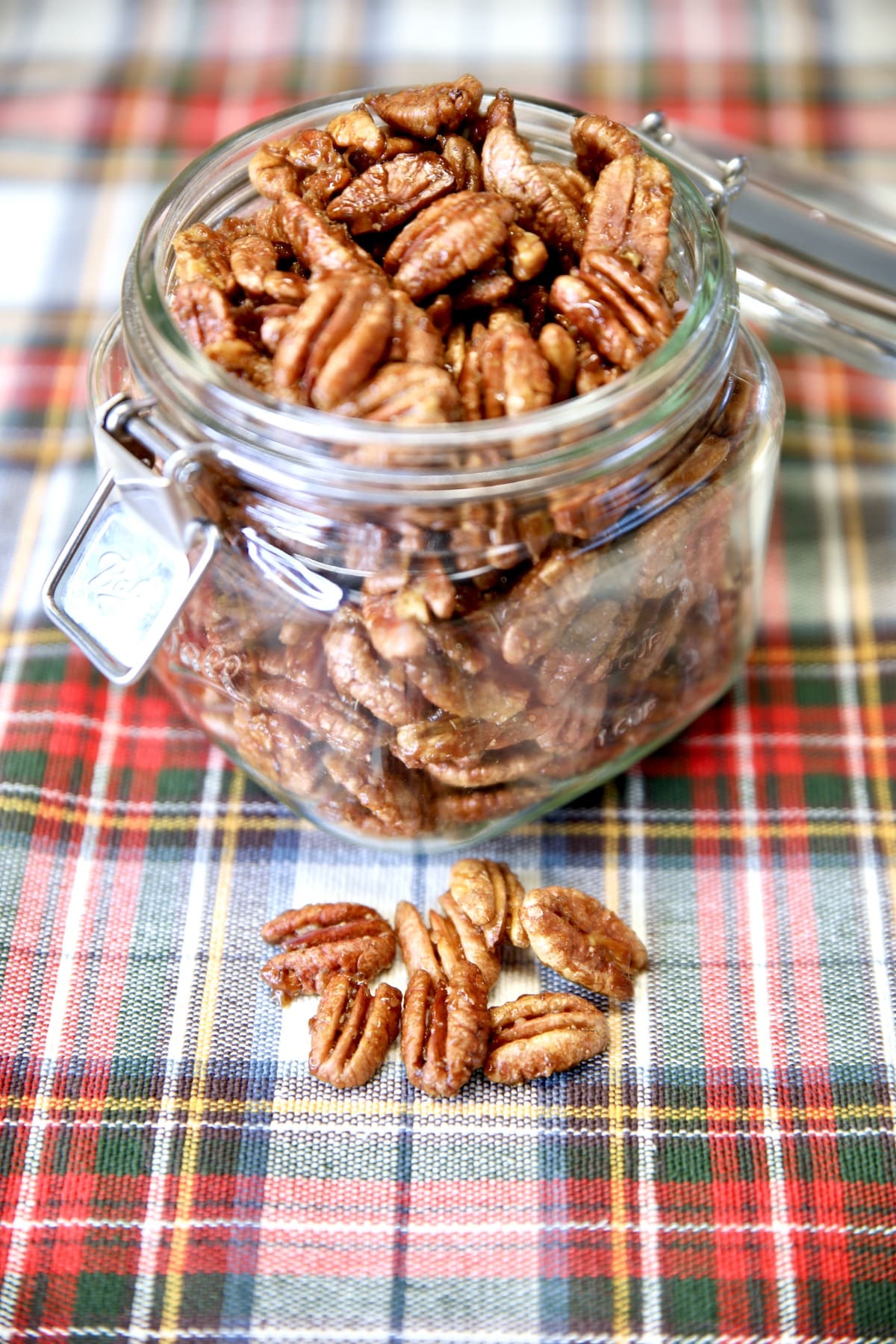 Jar of candied pecans, a few in front of the jar.