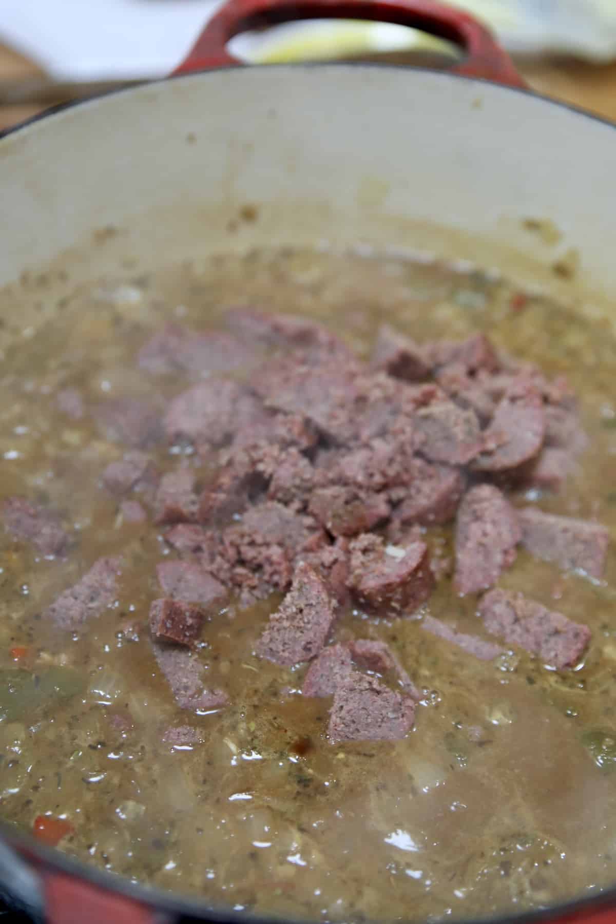 Adding chicken and smoked sausage to gumbo.
