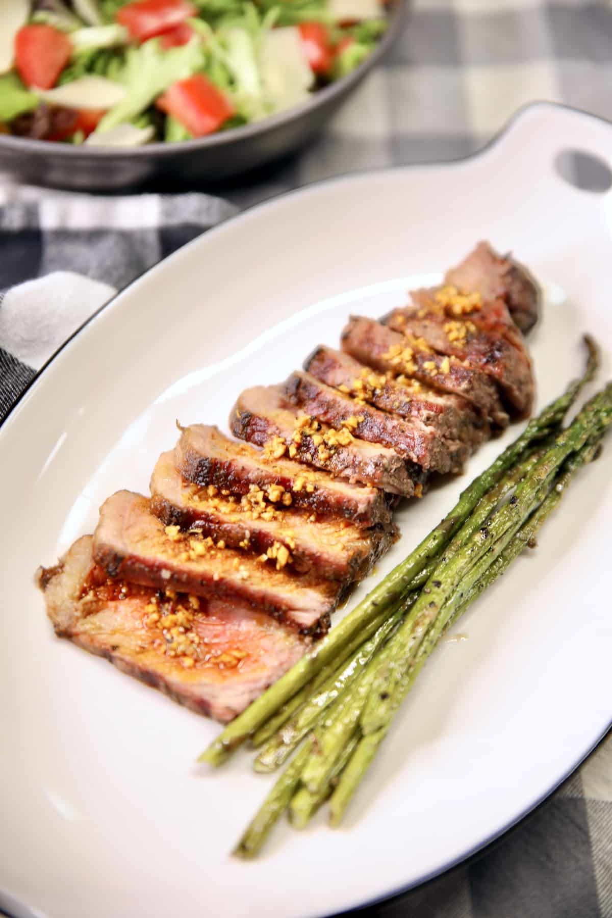 Plate with sliced strip steak and asparagus.