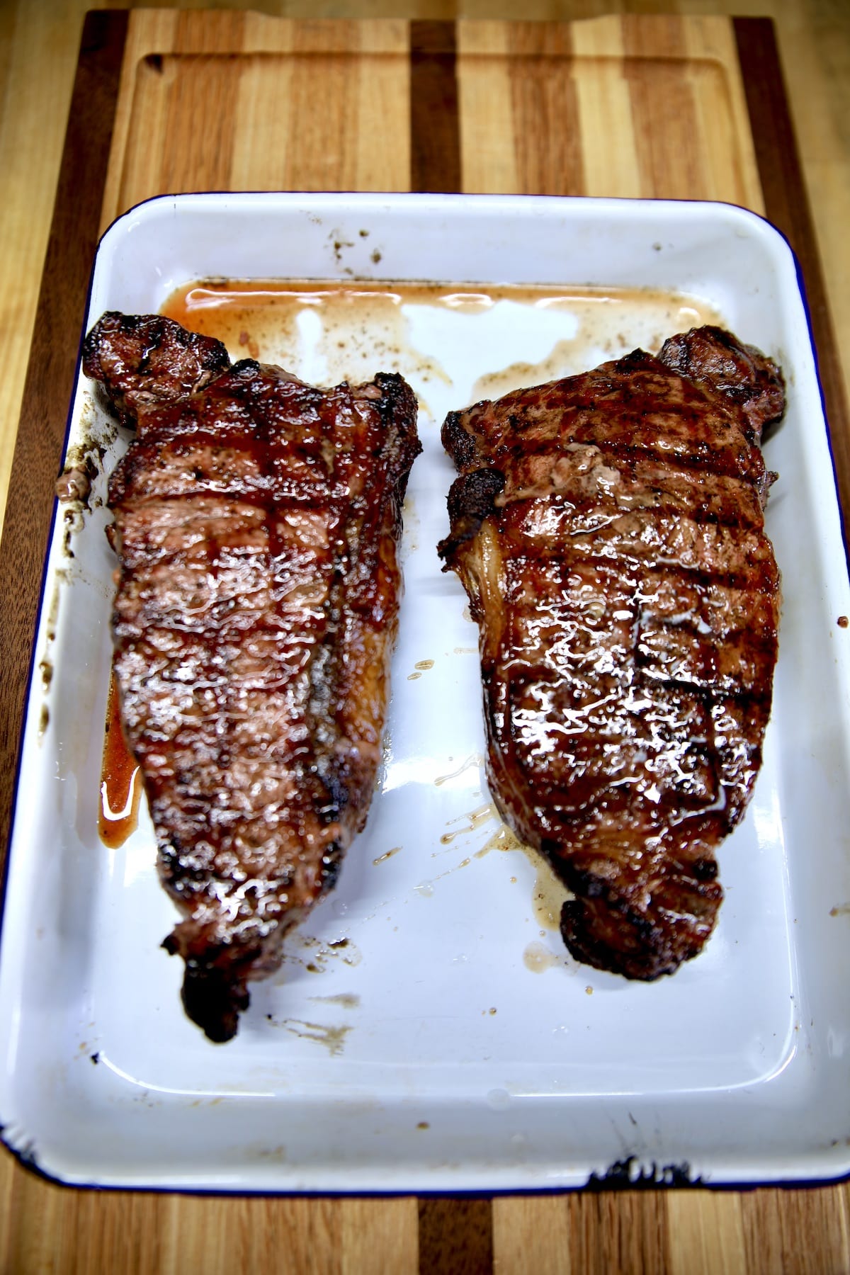 2 grilled NY Strip Steaks resting on a pan.