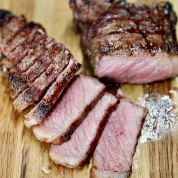 Medium Grilled Strip Steak, partially sliced on a cutting board.