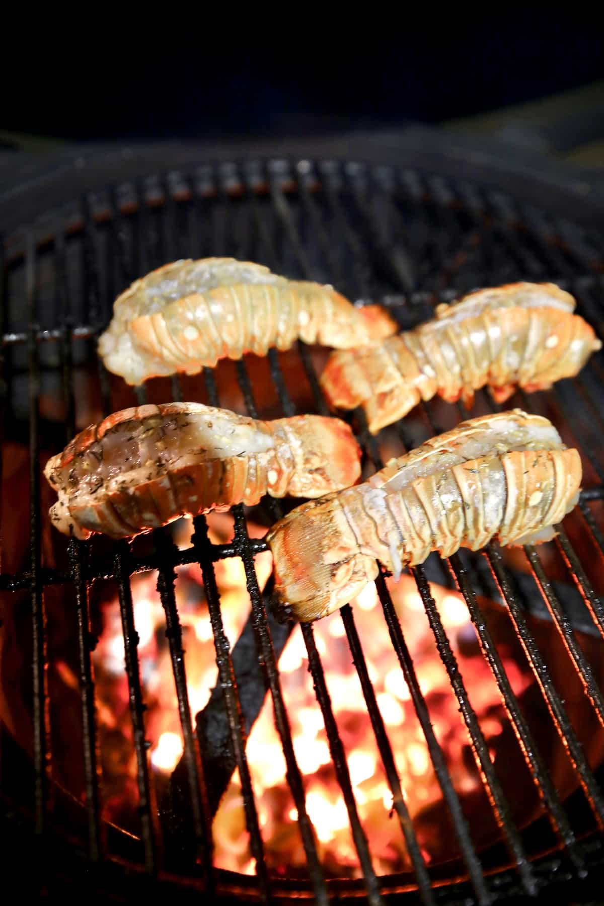 4 lobster tails on a grill.