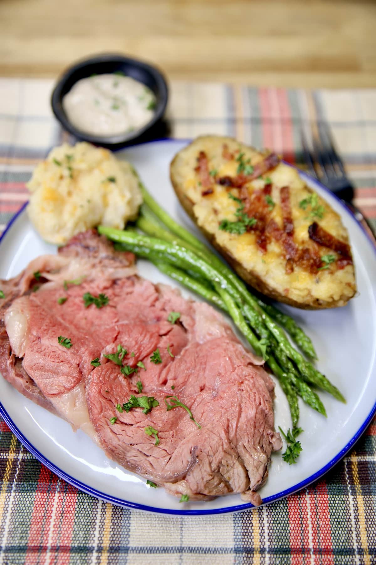 Plate with slice of prime rib, baked potato, asparagus.