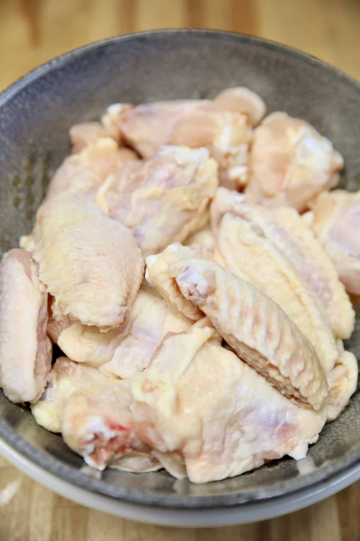 Raw chicken wings in a colander.