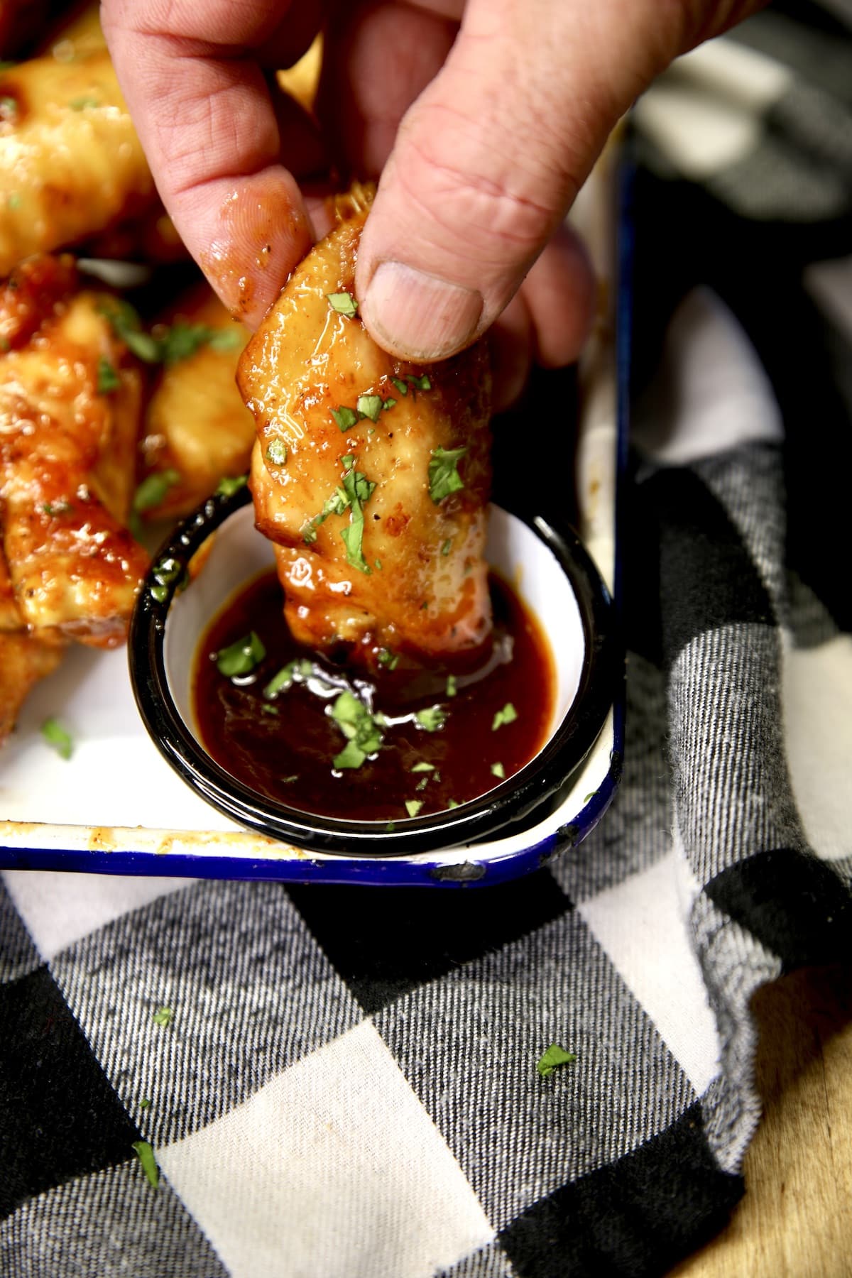 Dipping chicken wing into bbq sauce.
