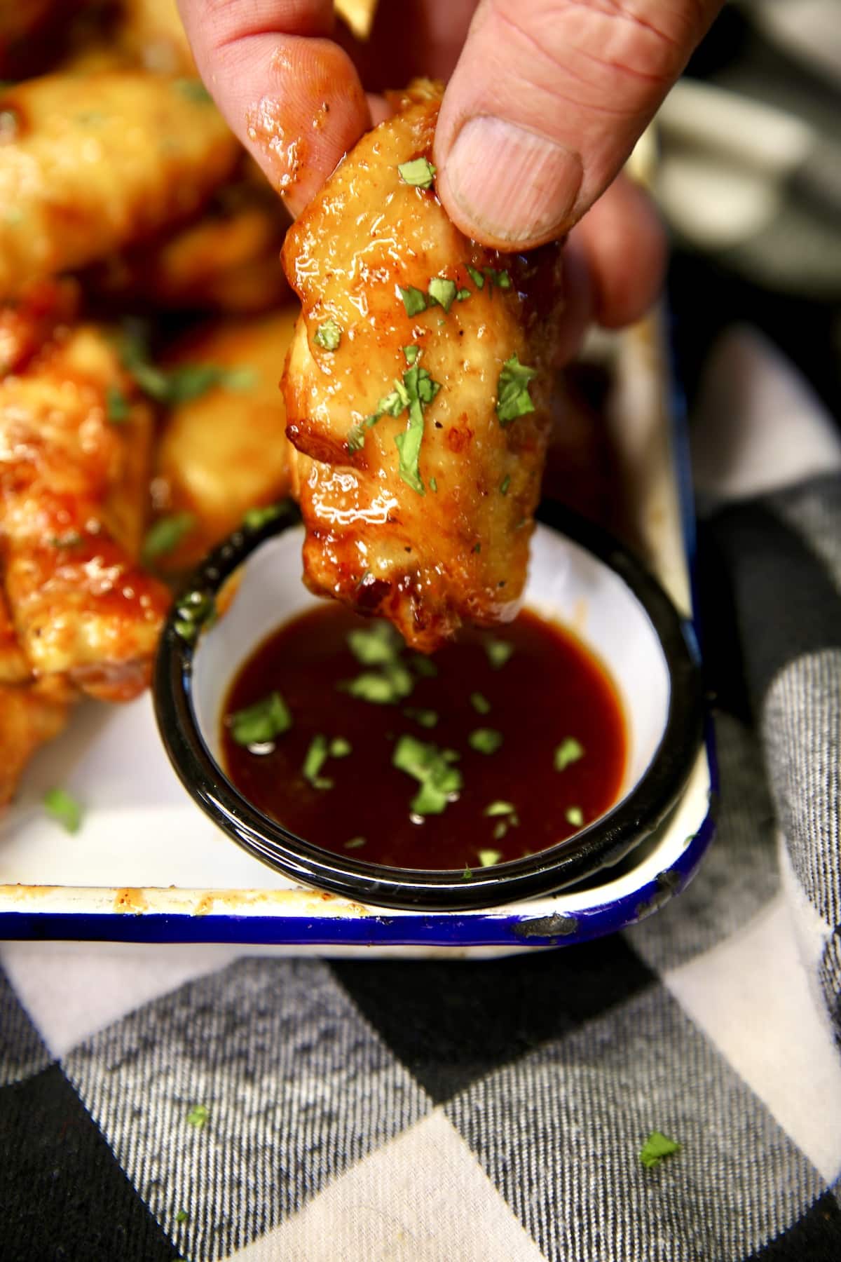 Dipping chicken wing into peach bbq sauce.