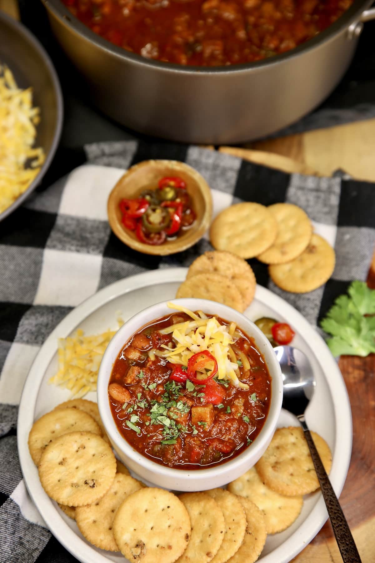 Bowl of chili on a plate with crackers.