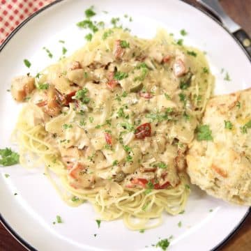Cajun chicken pasta on a plate with biscuit.