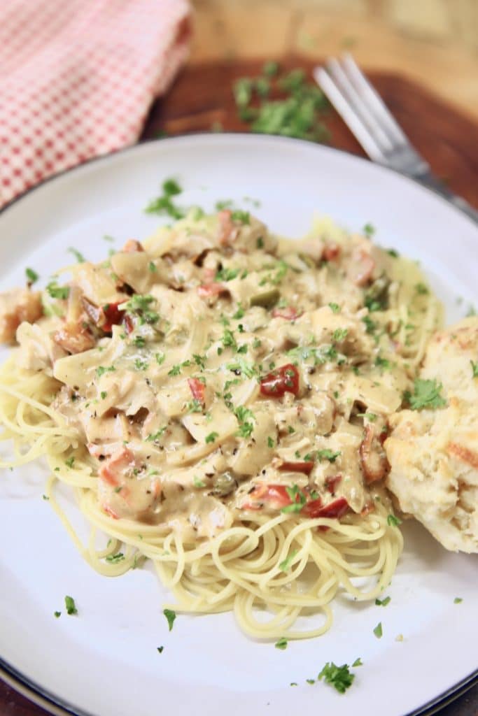 Plate of angel hair pasta topped with creamy chicken sauce.