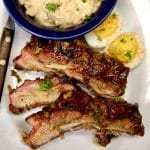 3 ribs on a plate with deviled eggs, potato salad.