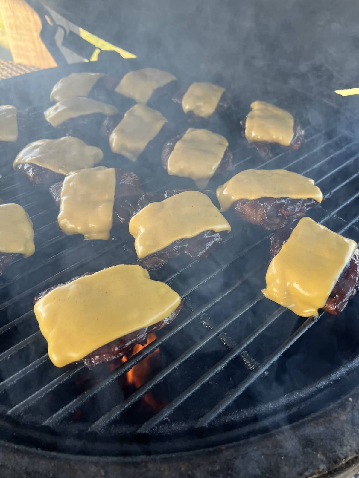 Burger sliders with cheese on a grill.