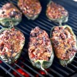 6 brisket stuffed poblano peppers on a grill.