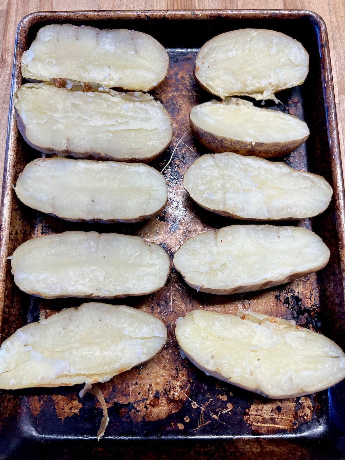 Baked potatoes sliced in half on a sheet pan.