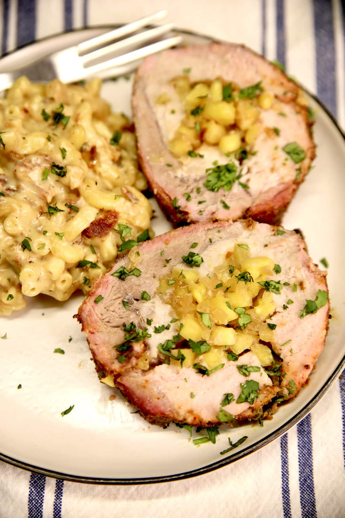 Plated 2 slices of pork loin stuffed with pineapple, mac and cheese.