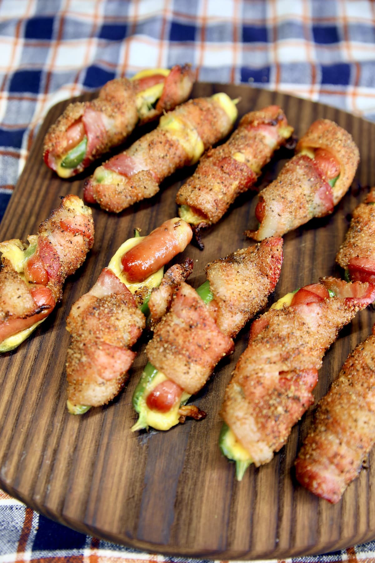 Cutting board with bacon wrapped sausage jalapeno poppers.