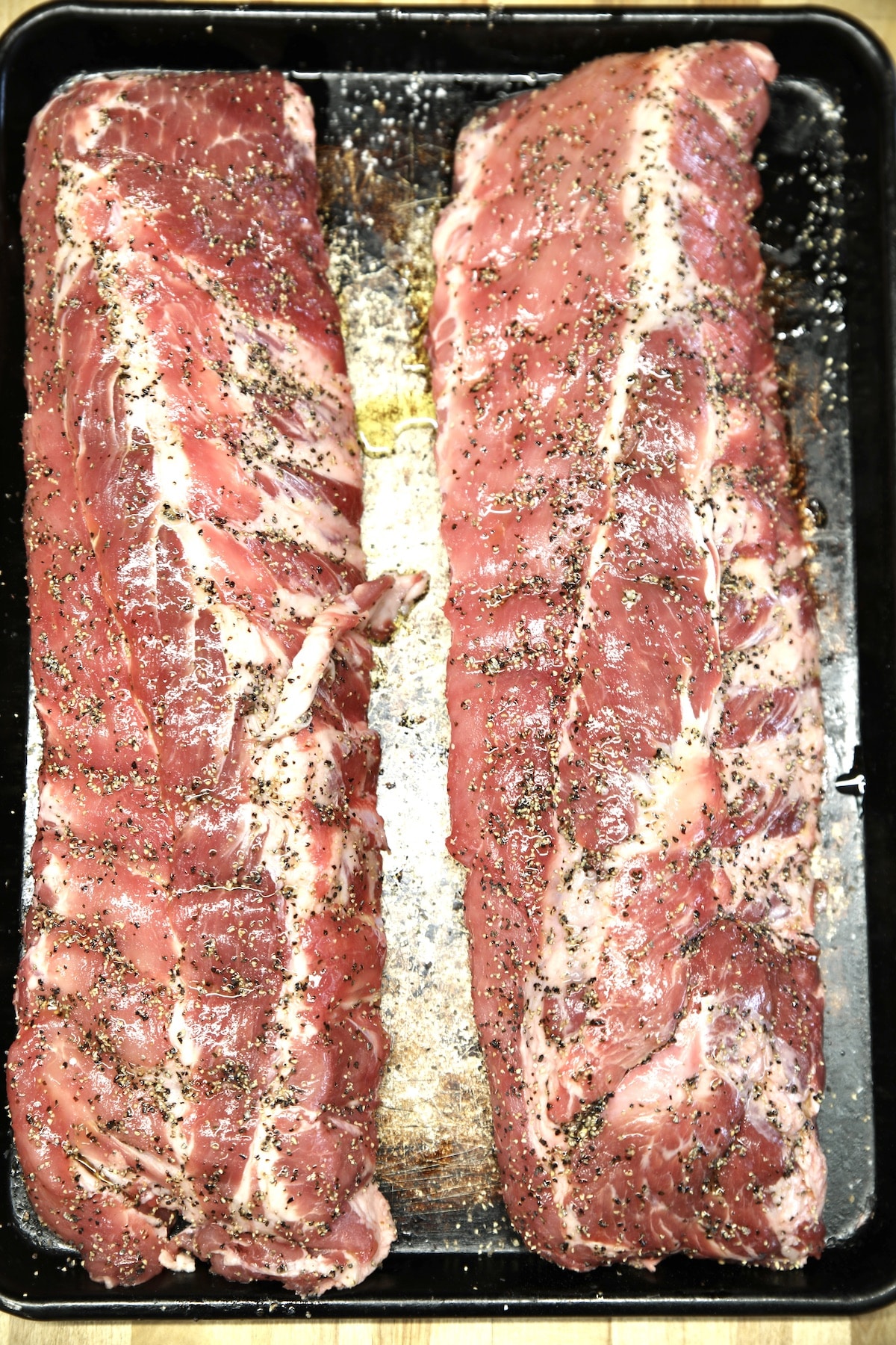 2 racks of baby back ribs - uncooked, with salt and pepper.