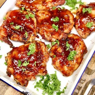 BBQ chicken thighs on a platter with parsley.