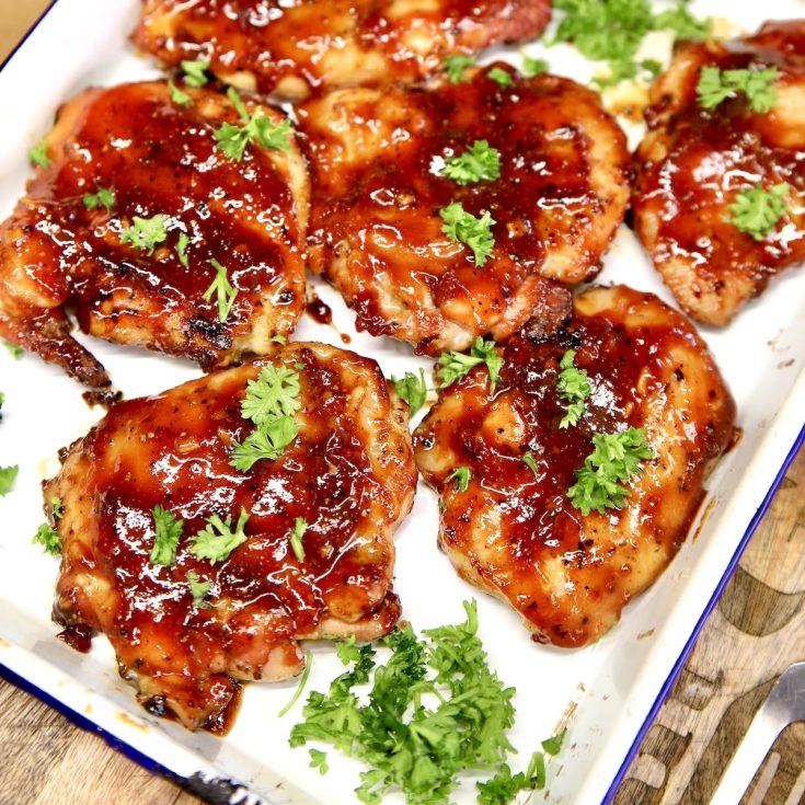 BBQ chicken thighs on a platter with parsley.