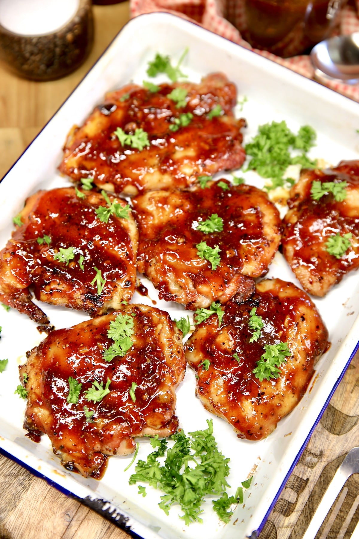Platter of bbq chicken thighs on a platter with parsley garnish.