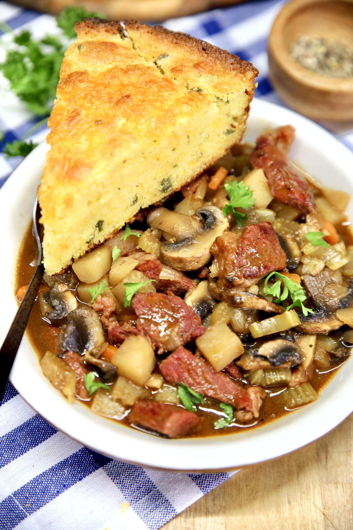 Beef mushroom stew in a bowl with slice of cornbread.