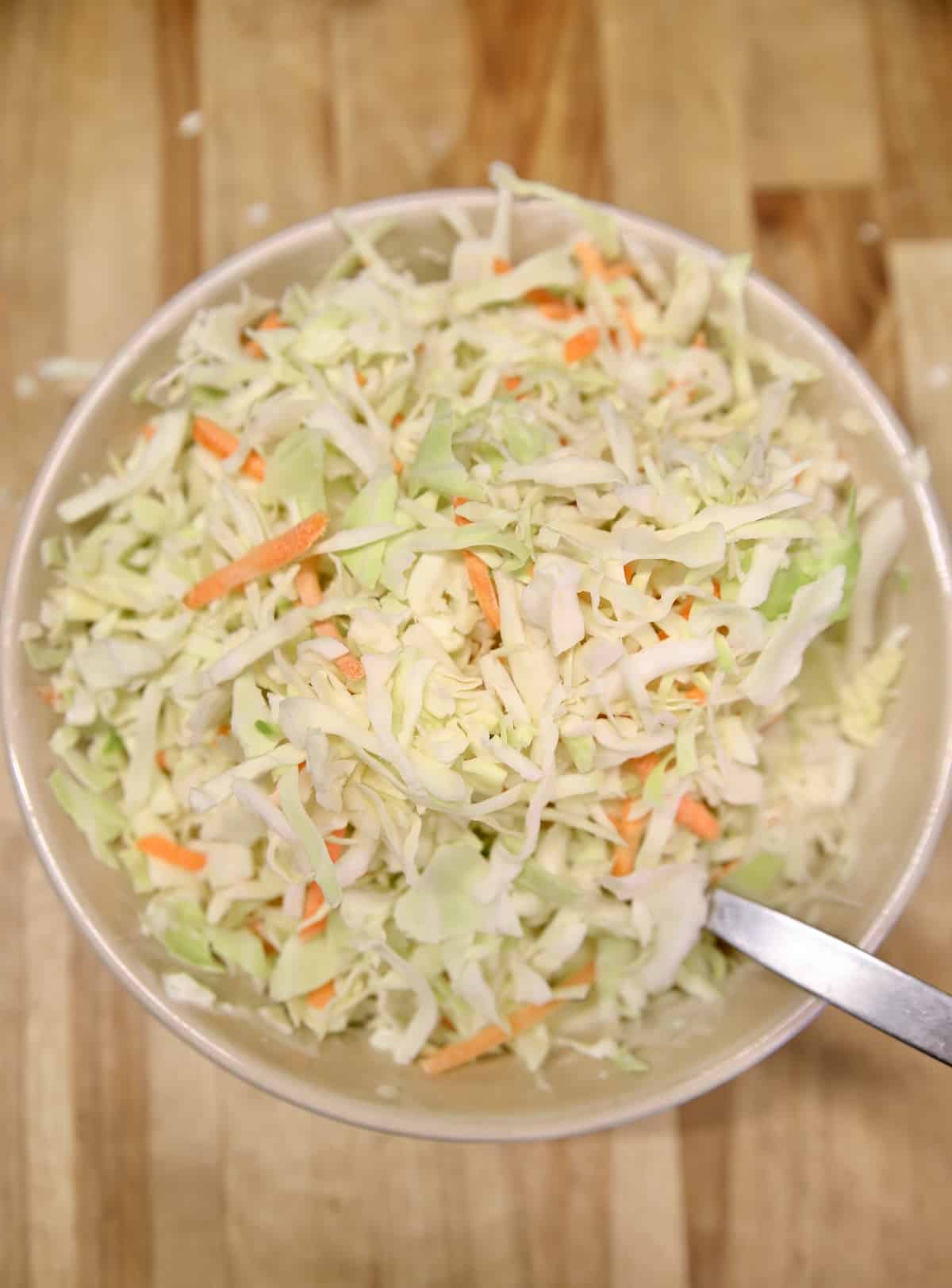 Bowl with cabbage, carrots, slaw dressing.
