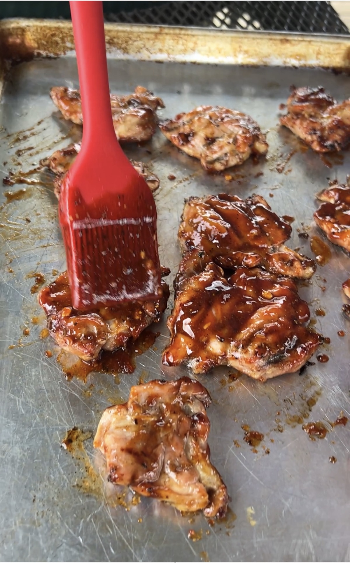 Brushing bbq sauce on grilled chicken.
