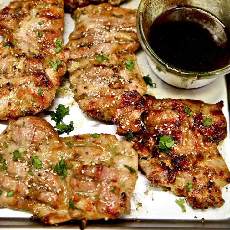 Grilled Asian Chicken with bowl of sauce on a sheet pan.