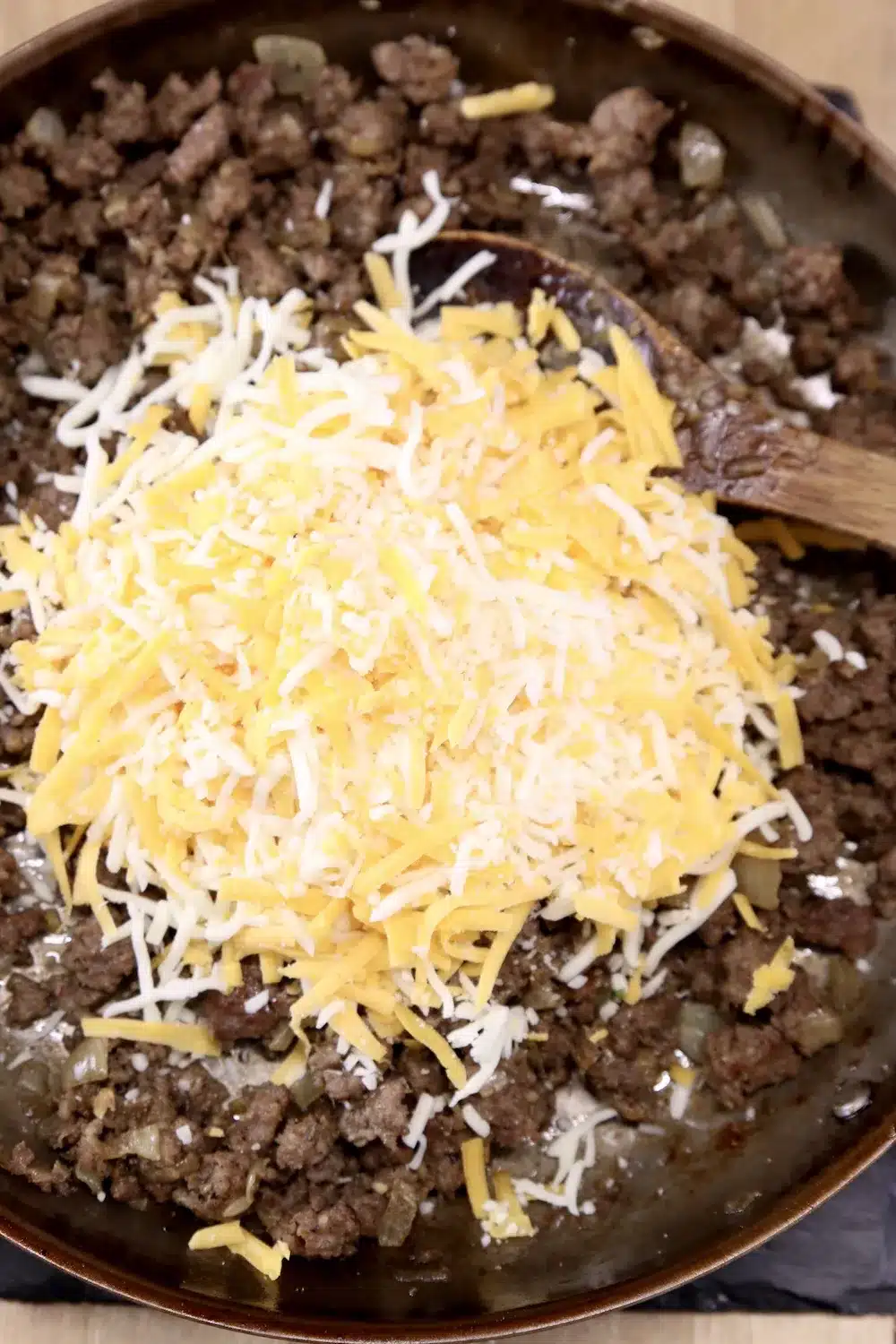 Skillet with browned sausage and grated cheese.