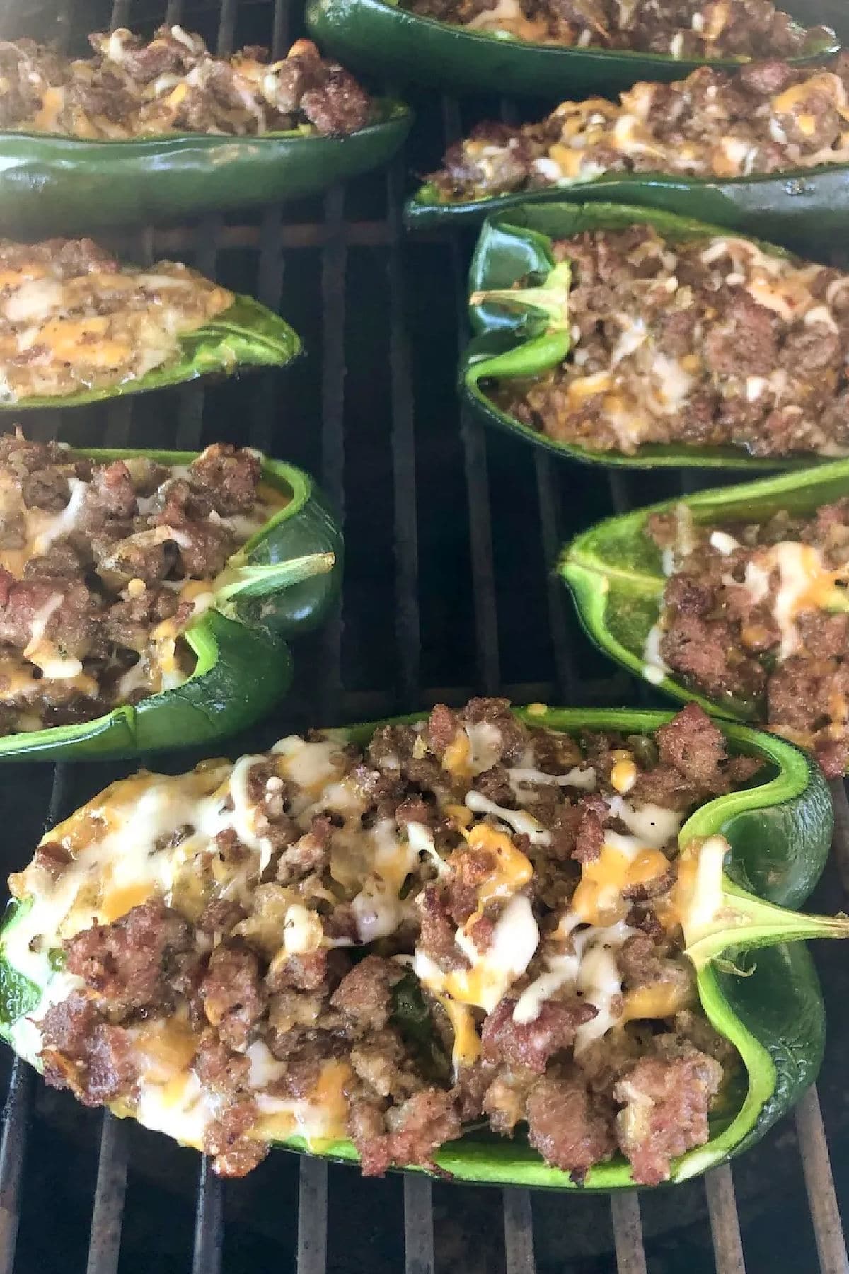 Close up of sausage stuffed peppers on a grill.