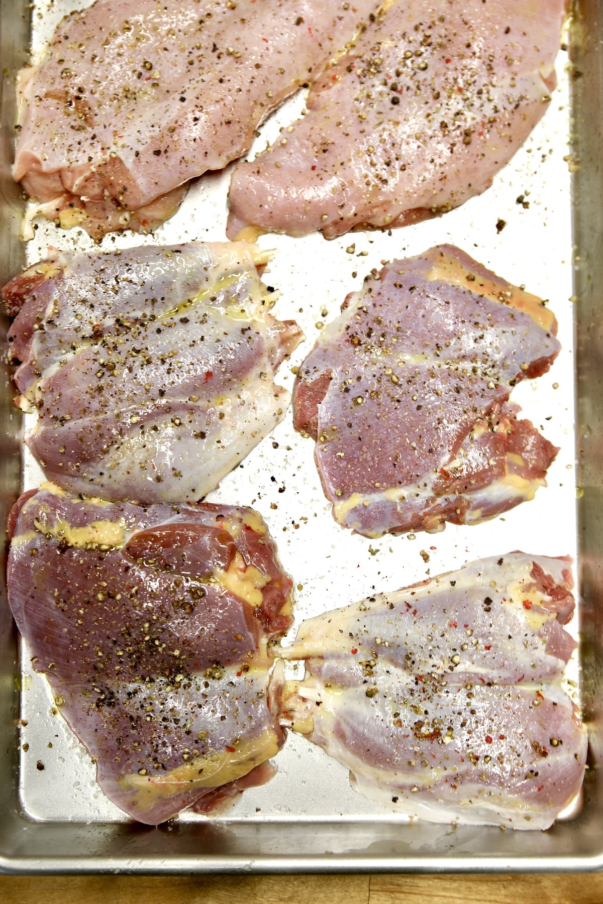 Sheet pan with boneless skinless chicken pieces.
