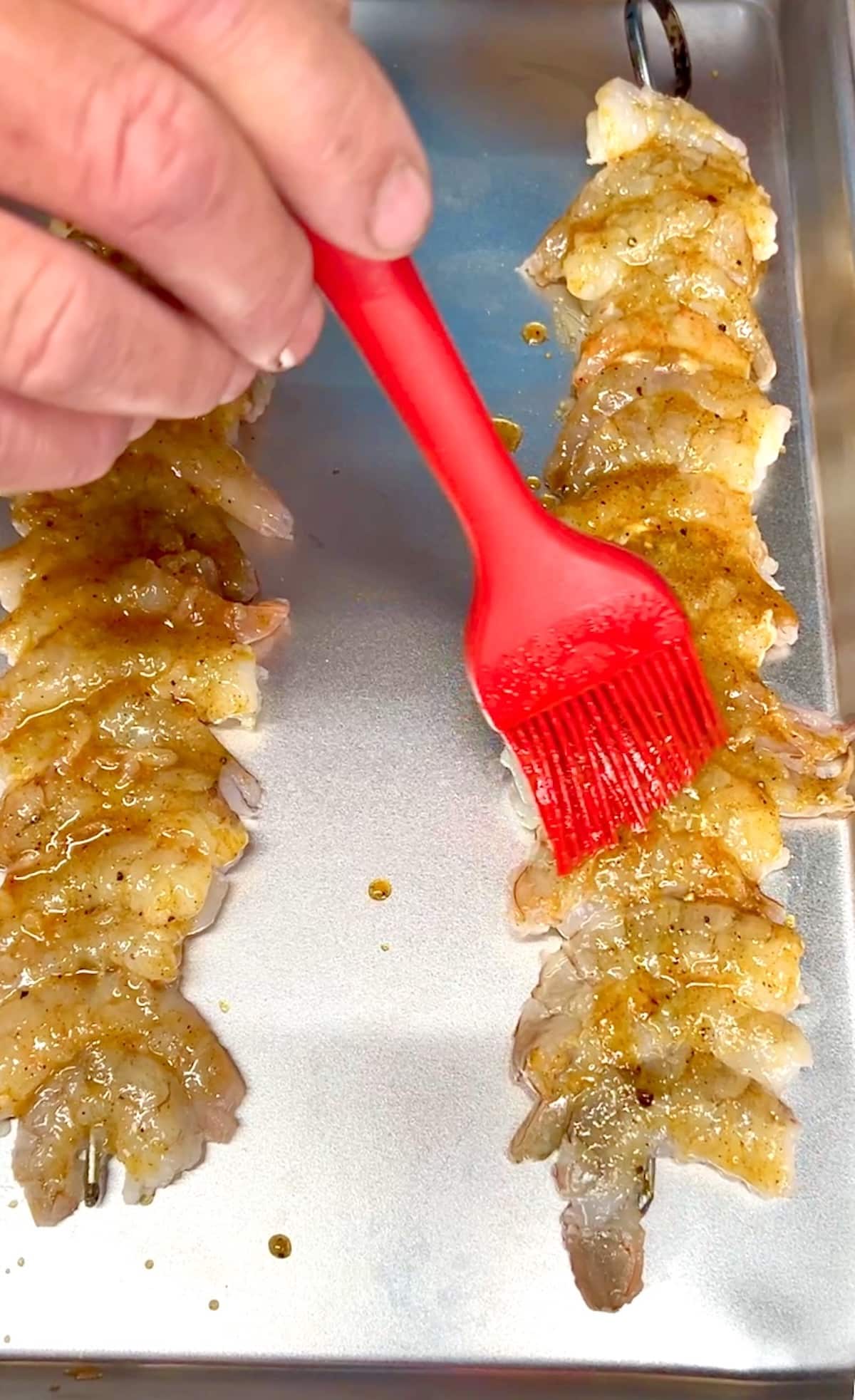 Brushing sauce over shrimp on skewers.