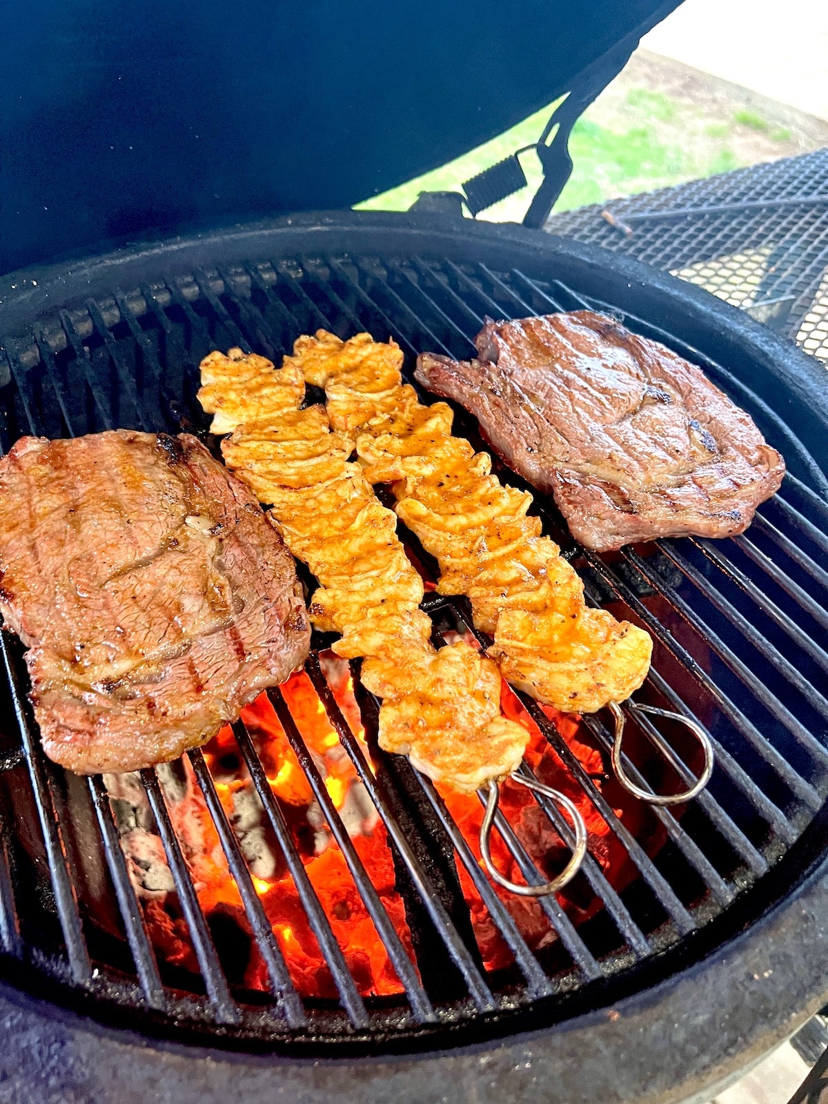 2 ribeyes with shrimp skewers on a grill.