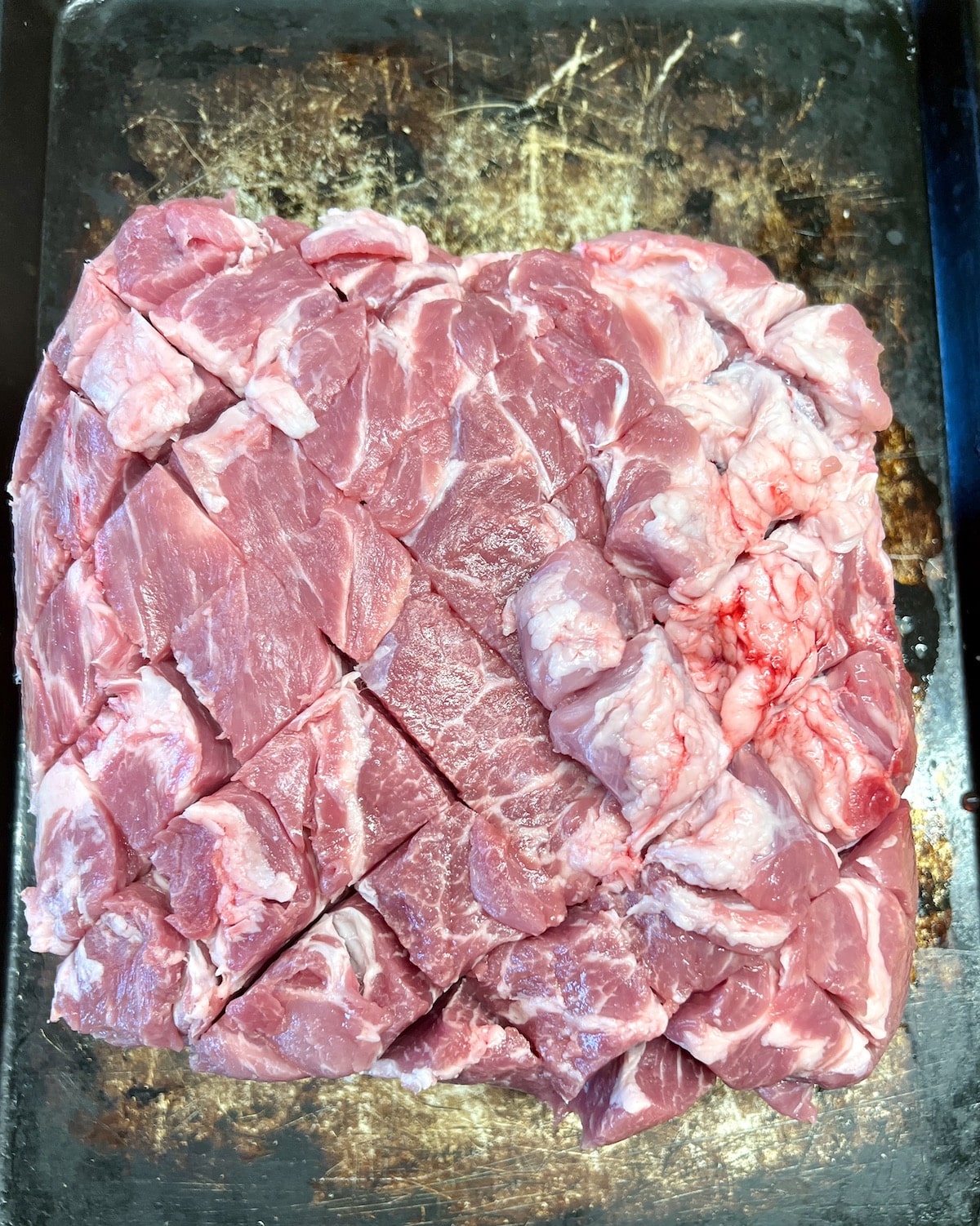 Pork butt, sliced in a crosshatch pattern for grilling.