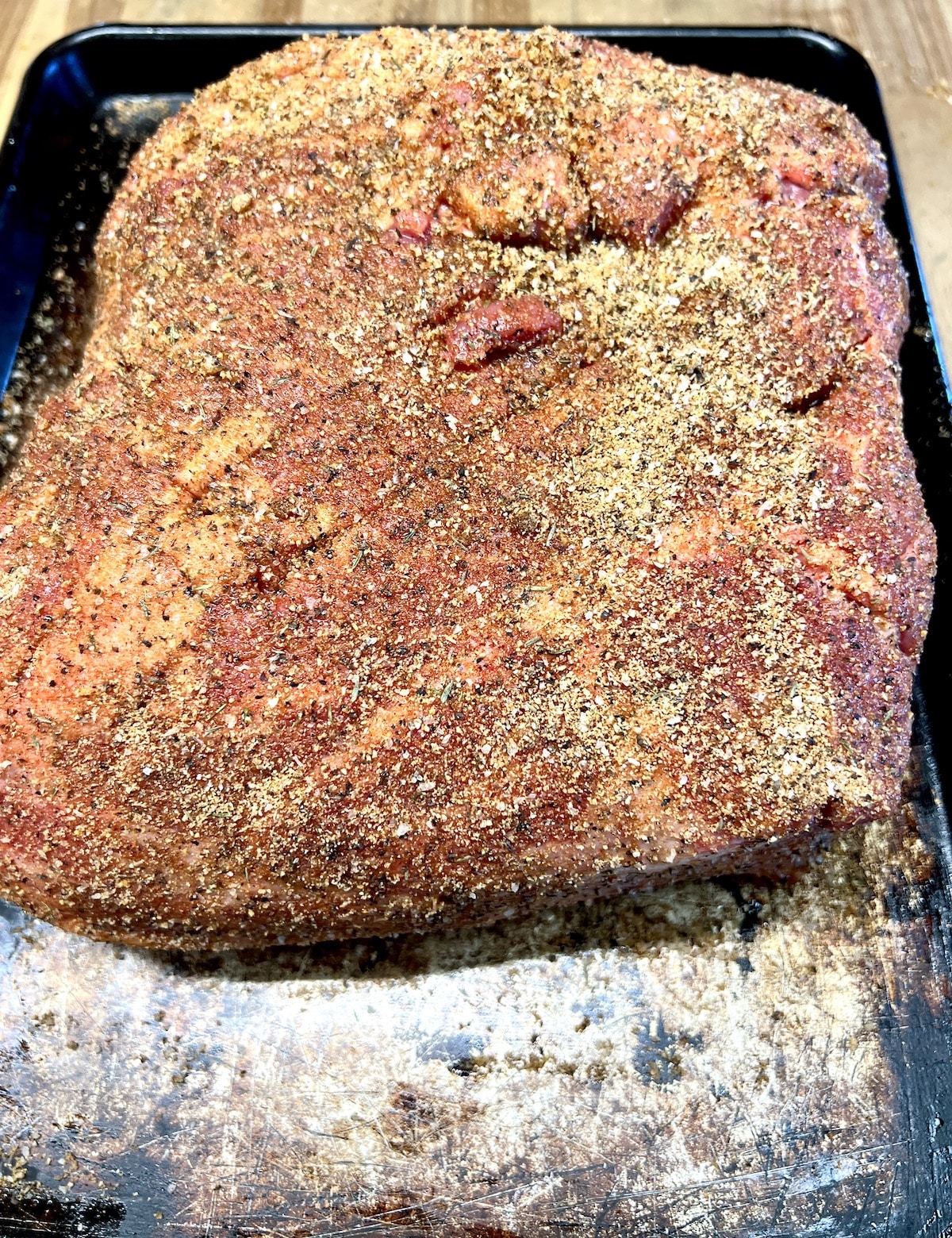Pork butt with dry rub on a sheet pan ready to grill.