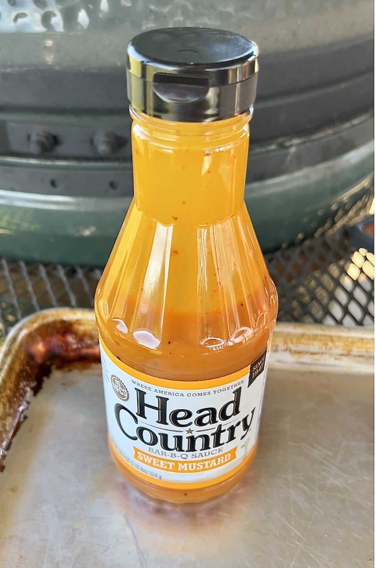 Head Country Sweet Mustard BBQ sauce in front of Big Green Egg grill.