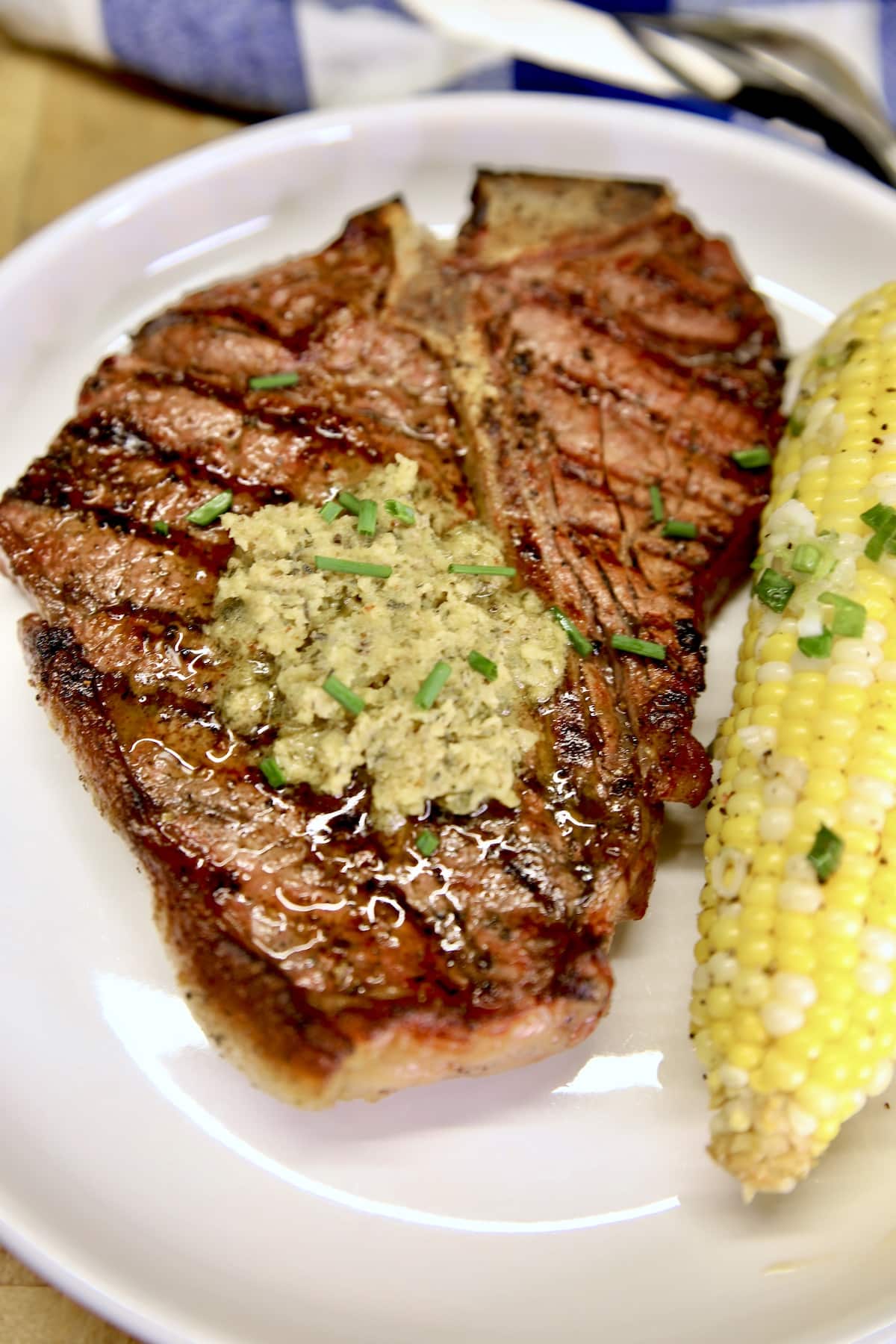 Steak with garlic and herb butter, corn on the cob.