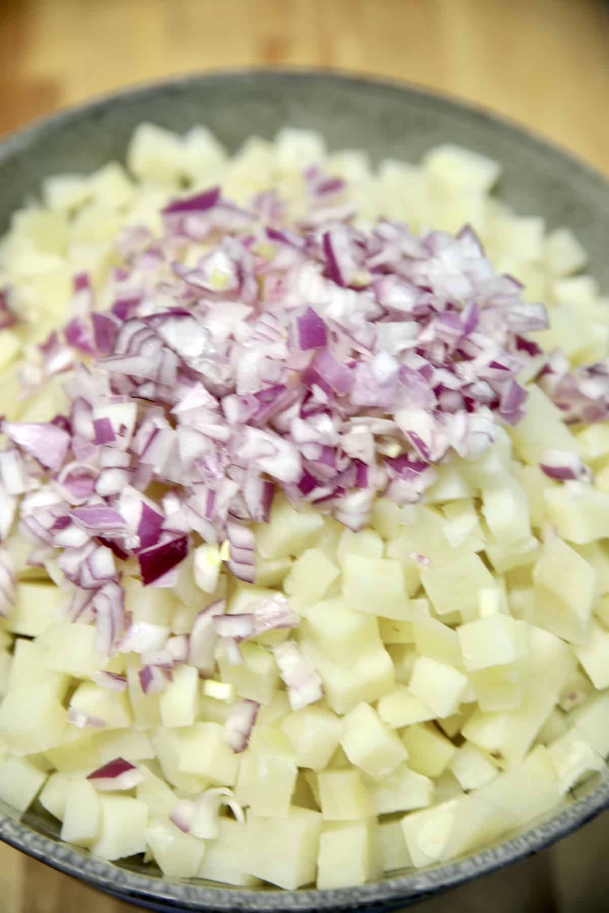 Diced potatoes in a colander with diced red onion.