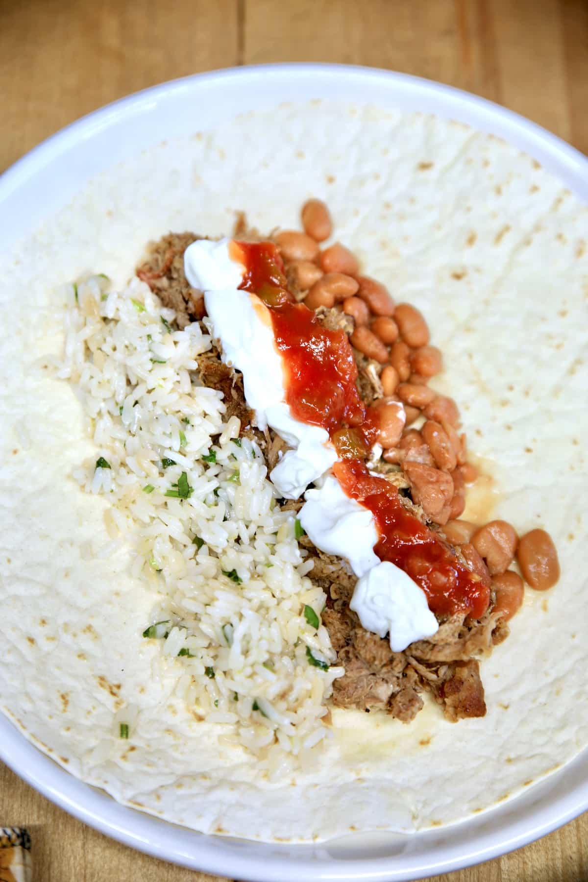 Burrito with pulled pork, rice, beans, salsa and sour cream.