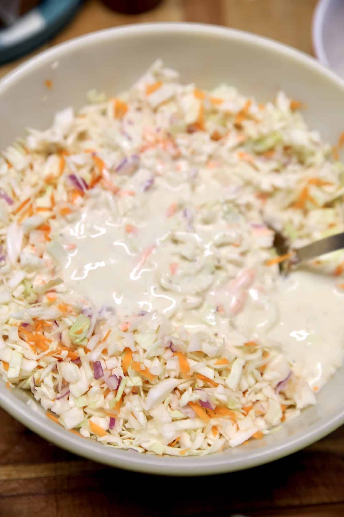 Making coleslaw in a bowl with dressing.
