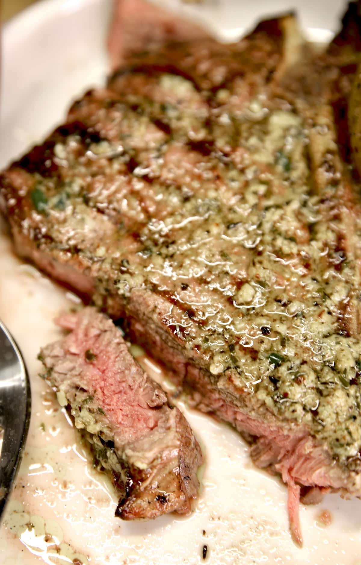 T-Bone steak with herb butter, slice on a plate.