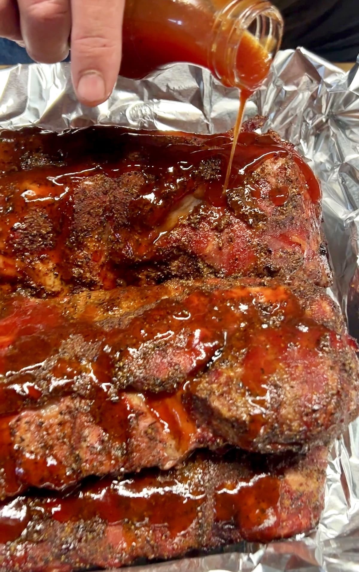 Pouring bbq sauce over Pork ribs.