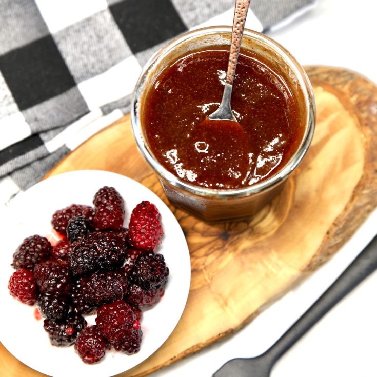 Blackberry bbq sauce in a jar with spoon, bowl of blackberries.