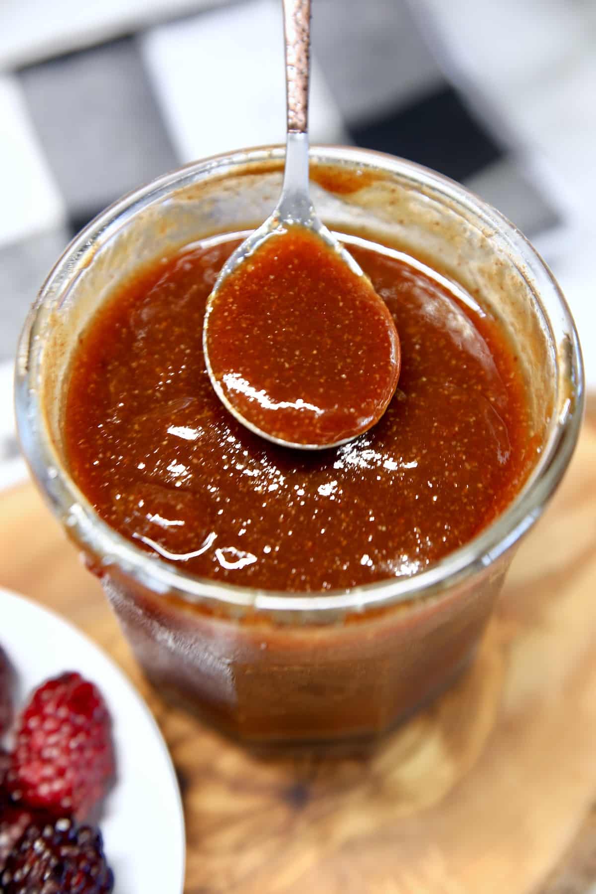 Jar of blackberry bbq sauce with a spoon dipping.