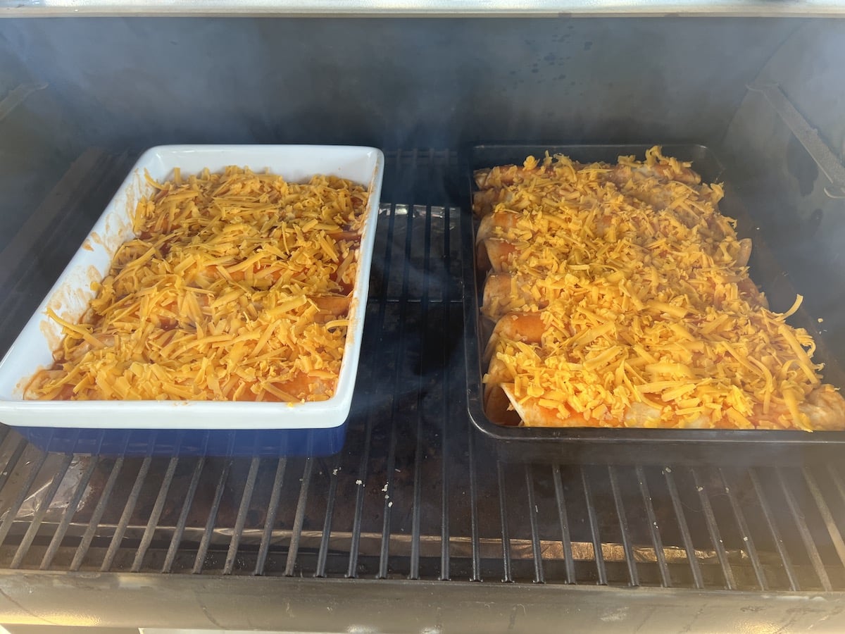 Pellet grill with 2 pans of enchiladas.