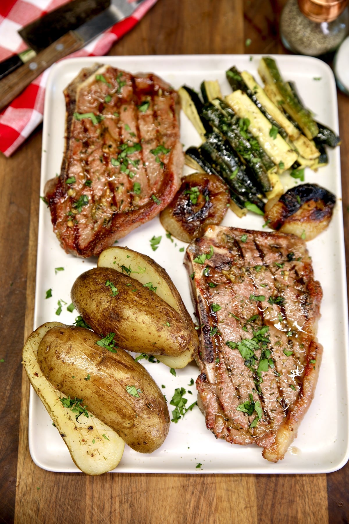 Platter of grilled steaks with potatoes and zucchini.
